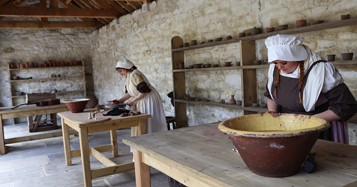 Two woman dressed in Georgian costumes creating pottery in the Georgian potter at Beamish Museum